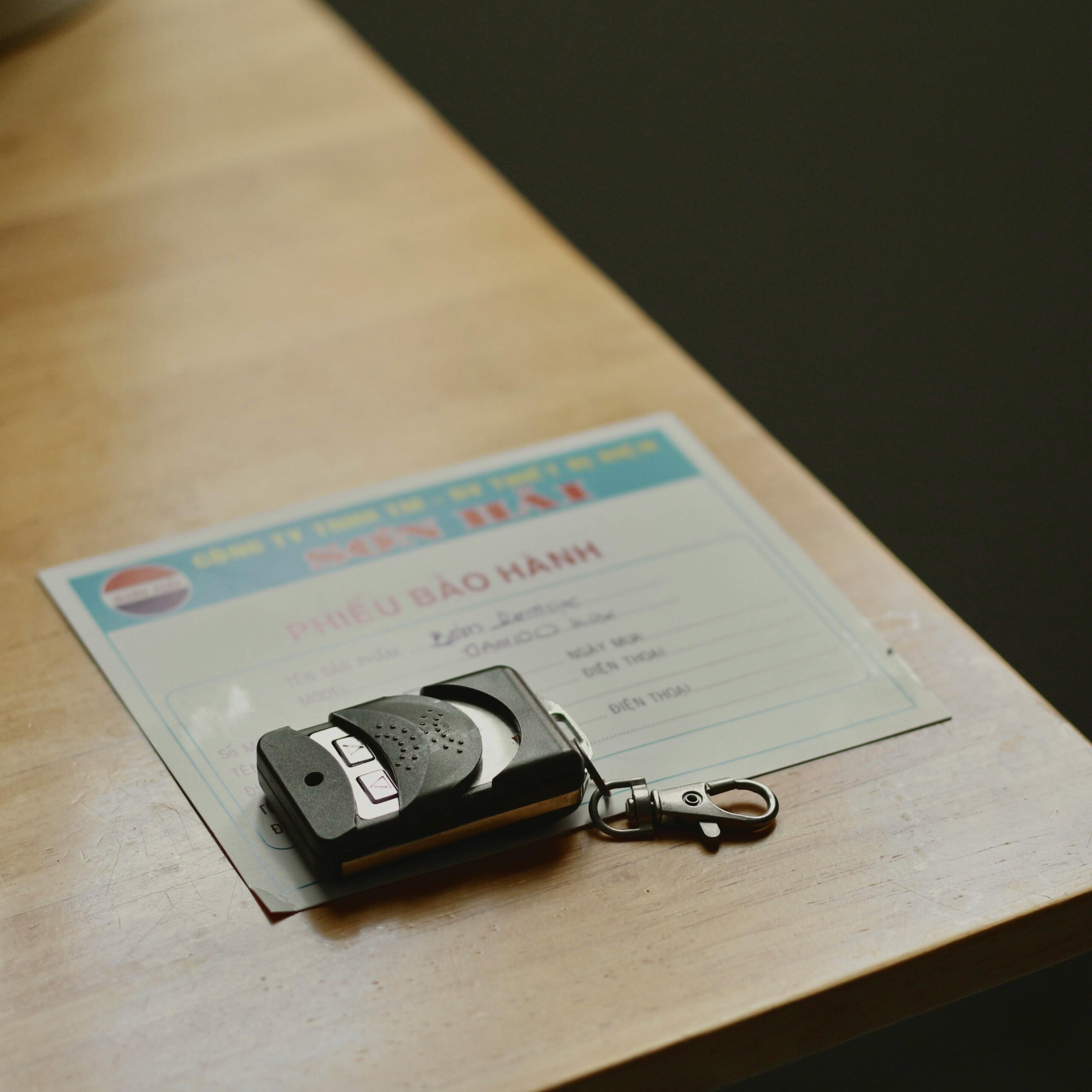 Remote control device resting on a warranty document placed on a wooden table.
